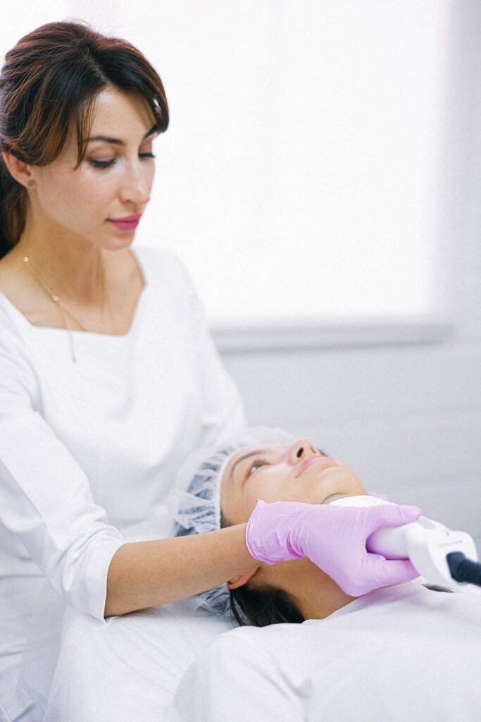 Aesthetician in a clinic using laser technology for a facial skin treatment on a patient.